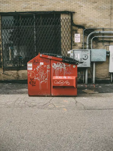 Red dumpster with graffiti in a city alley